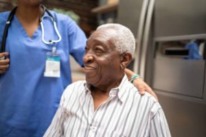 Senior man sitting, nurse behind him